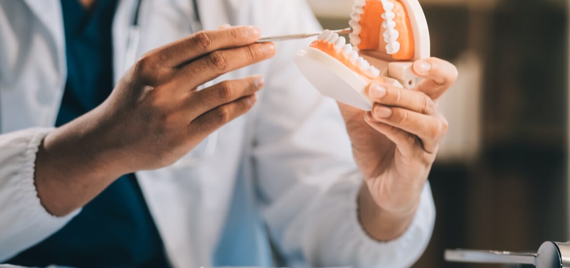 doctor showing a denture model to a patient in Alexandria